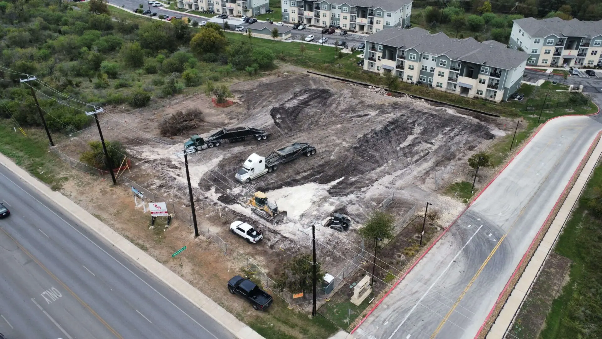 Construction site with vehicles and nearby road.