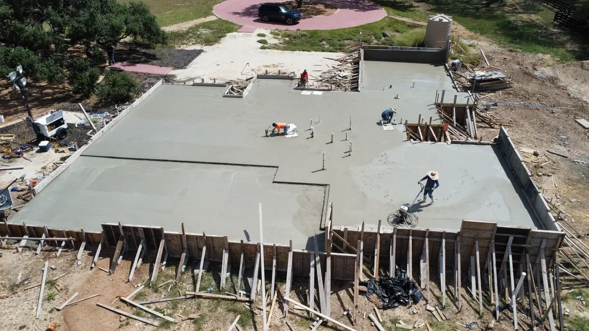 Construction workers smoothing fresh concrete foundation.