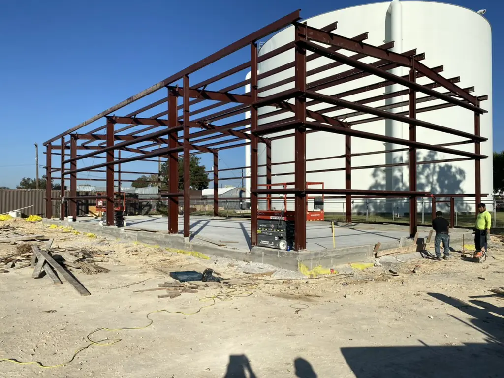 Steel frame structure under construction, clear sky.