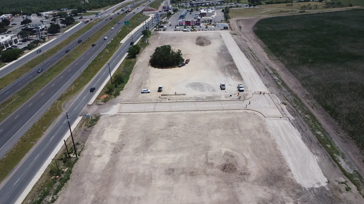 Construction site beside a highway and field.