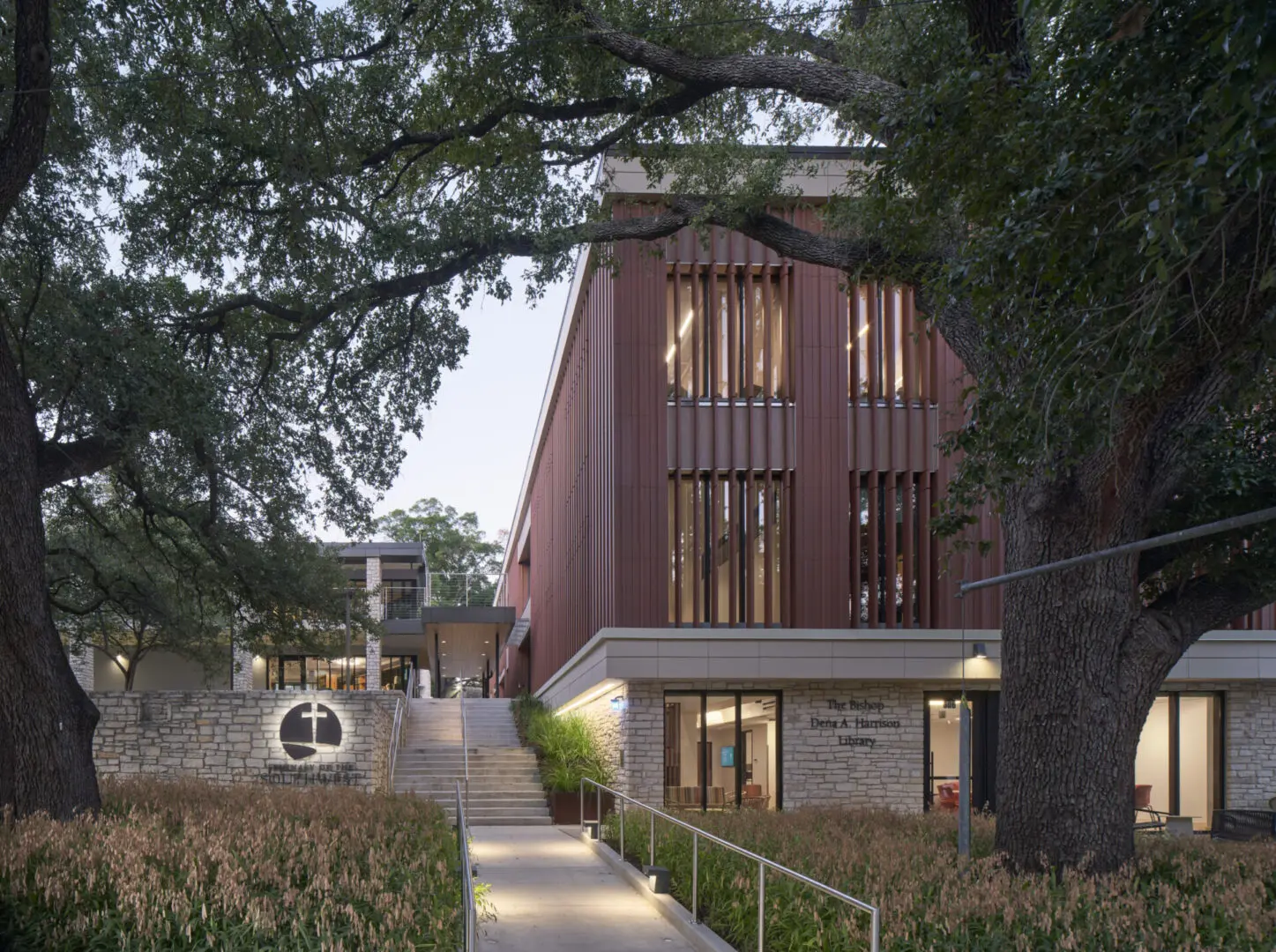 Modern building surrounded by trees and walkway.